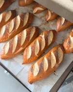 מתכון חדש ללחמניות פרעצל קלות להכנה והכי טעימות שיש, שמרו את המתכון הזה

לחמניות פרעצל

חומרים לבצק 12 יחידות:

550 מ”ל מים (בקיץ מים קרים, בחורף מים פושרים)
10 גרם שמרים יבשים
60 גרם סוכר חום בהיר דמררה
קילו קמח לחם מנופה
50 מ”ל שמן זית
28 גרם מלח

לציפוי:
פרג/מלח גס

לבישול הפרעצל:
4 ליטר מים + 2 כפות אבקת סודה לשתייה+ חצי כוס סילאן

אופן ההכנה;
שמים בקערת המיקסר עם וו לישה מים, שמרים, סוכר ומערבבים כחצי דקה
מוסיפים קמח ומערבלים למשך 2 דקות על מהירות נמוכה- בינונית עד להיווצרות בצק
מוסיפים שמן ומלח ולשים 8 דקות נוספות
הבצק צריך להיות אחיד, חלק וגמיש למגע
התפחה: מעבירים את הבצק לקערה משומנת מעט ומכוסה במגבת ונותנים לבצק לתפוח 30-50 דקות
שקילה: מחלקים את הבצק ל 12 יחידות, כל יחידה שוקלת 145 גרם
עיצוב: מרדדים בעזרת מערוך כל חתיכת בצק למלבן, מבצעים ארבעה עד חמישה קיפולים כלפי פנים ע”מ ליצור גליל מהודק, מרדדים מעט את קצוות הלחמניה עם הידיים ליצירת קצוות מחודדים
בישול לחמניות הפרעצל: מביאים לרתיחה בסיר גדול את כל החומרים של מי הבישול: מים, אבקת סודה לשתייה וסילאן, מנמיכים את האש ומבשלים בסיר בשלישיות למשך 30 שניות, עד אשר לחמניות הפרעצל צפות למעלה, מוציאים בעזרת כף מחוררת לתבנית עם נייר אפיה מעט שומן, מניחים את הלחמניות במרווחים אחת מהשנייה
חורצים את הלחמניות בעזרת תער חד 4 חריצים אלכסונים
מפזרים פרג/ מלח ים
אפייה: אופים בתנור שחומם מראש לחום של 215 מעלות למשך כ- 20 דקות עד להזהבה יפה

#pretzelroll #pretzels #bakingtime #מתכון #פרעצל #אפיה #יאמי #מתכוןמנצח