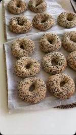 בייגלס מצופים במלא שומשום זו אהבה שלי, תשמרו את המתכון הזה

החומרים:
קילו קמח לחם מנופה
20 גרם שמרים יבשים
20 גרם סוכר
630 מ”ל מים
30 מ”ל שמן זית
28 גרם מלח

לציפוי:
שומשום
מים

אופן ההכנה:
בקערת המיקסר עם וו לישה שמים מים, שמרים, סוכר ומערבבים עם מטרפה, ממתינים דקה
מוסיפים קמח ולשים עד שנוצר בצק (כשתי דקות לערך)
מוסיפים בהדרגה תוך כדי לישה שמן זית ולשים 6 דקות על מהירות נמוכה- בינונית
מוסיפים את המלח ולשים 2 דקות נוספות על מהירות גבוהה יותר
הבצק צריך להיות אחיד, חלק וגמיש למגע 
התפחה ראשונה: מוציאים את הבצק מהקערה, מעצבים לצורת כדור, שמים בקערה משומנת מעט ומתפיחים כשעה וחצי או עד אשר הבצק מכפיל את נפחו, מכוסה
שקילה: מחלקים את הבצק ל-14 יחידות, כל יחידה במשקל 120 גרם
עיצוב ראשוני ומנוחה: יוצרים כדור מתוח ויפה מכל חתיכת בצק, מניחים את הכדורים על שיש מעט משומן במרווחים אחד מהשני, מכסים וממתינים כ-30-60 דקות
ציפוי: מכינים 2 קערות, קערה ראשונה עם מים, קערה שנייה עם הרבה שומשום, טובלים כל כדור בצק בקערת המים ואח”כ שמים בקערת השומשום ומצפים היטב מכל הצדדים, מניחים על השיש
עיצוב סופי: בעזרת הידיים עושים חור באמצע בכל כדור ולאט לאט פותחים אותו לצורה של בייגלה 
התפחה שנייה: מניחים את הבייגל במרווחים אחד מהשני על תבנית עם נייר אפייה ומתפיחים כחצי שעה מכוסים
אפייה: בתנור שחומם מראש לחום של -190 מעלות אופים את הבייגל כ-20-25 דקות עד להזהבה יפה
#bagels #sesamebagel #baking #bakingwithlove #yum